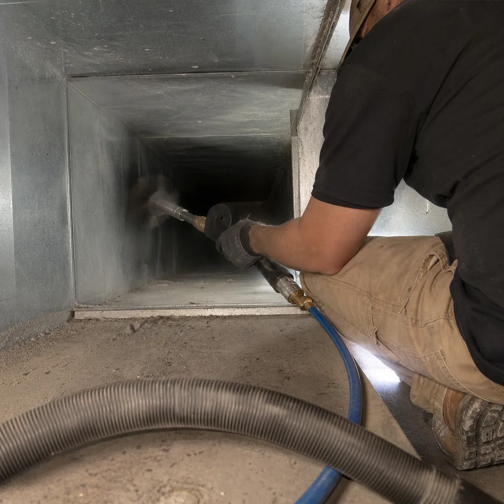 Technician using professional rotating brush tool for residential air duct cleaning